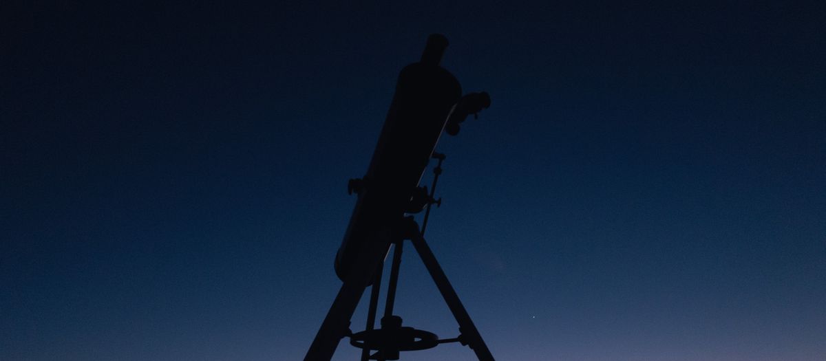 Silhouette of a telescope against a twilight sky, perfect for astronomy enthusiasts.