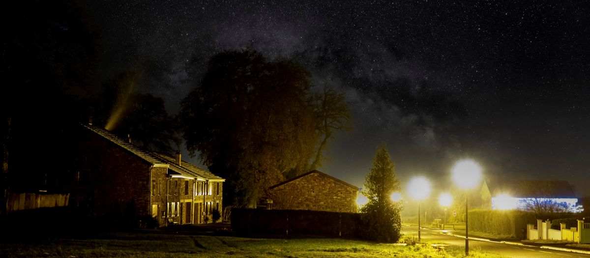 Tranquil suburban street under a mesmerizing starry night sky, showcasing serene neighborhood charm.