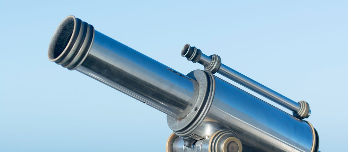 A sleek metallic coin-operated telescope pointing into a clear blue sky, perfect day for sightseeing.